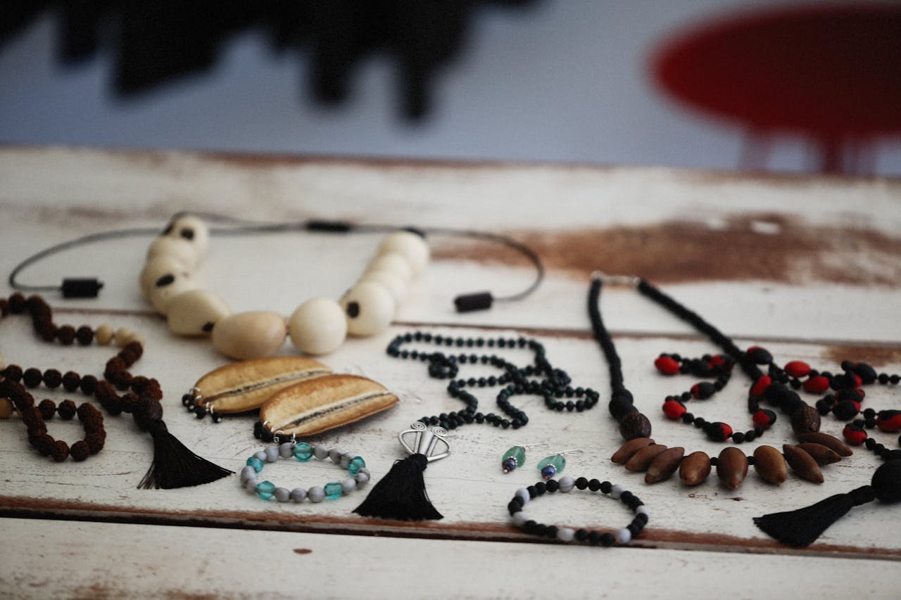 A collection of handmade necklaces and bracelets displayed on a rustic wooden table.